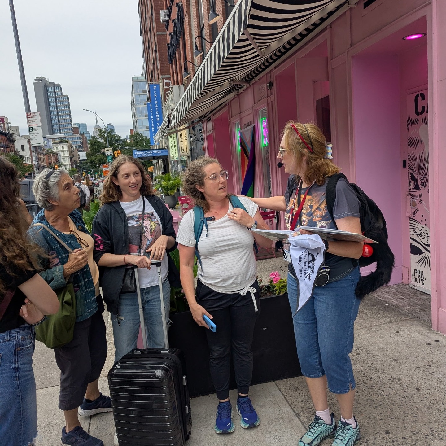 Tour guide speaking with guests outside pink Chinatown storefront