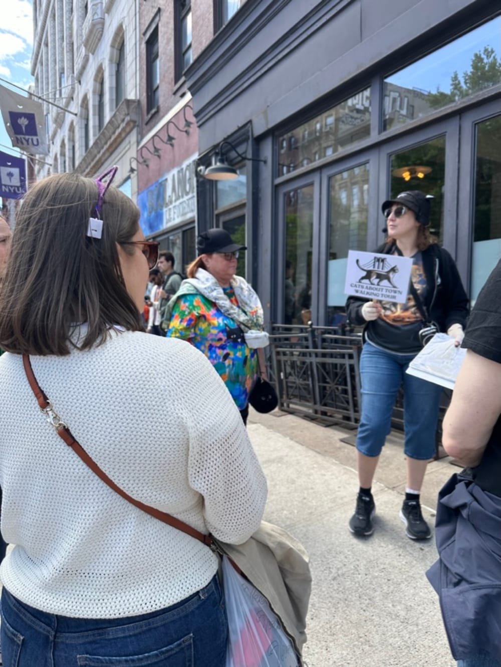 Tour assistant showing Cats About Town sign near NYU