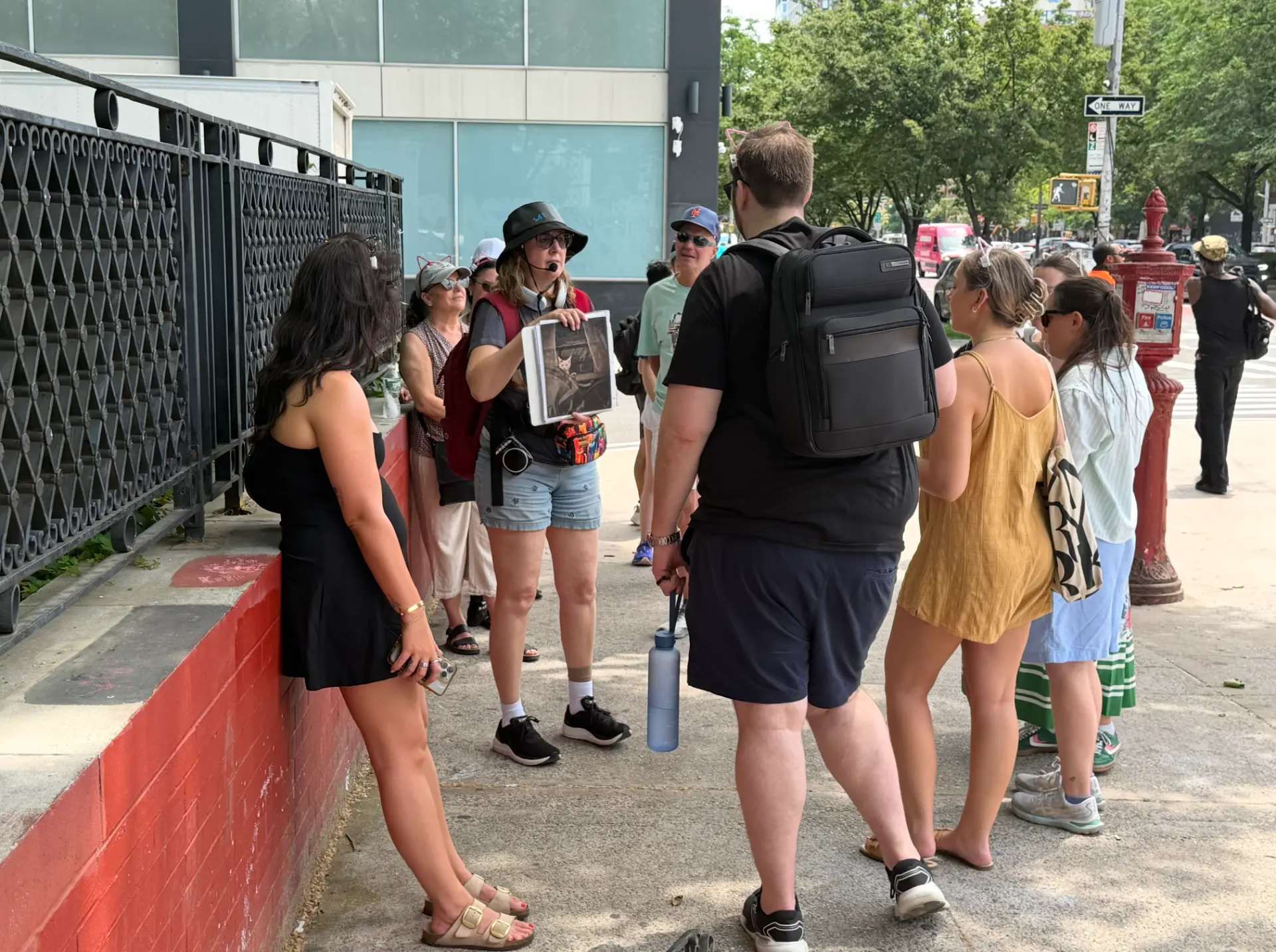 Cats About Town guide shows a historic cat photograph to guests on a Lower East Side sidewalk