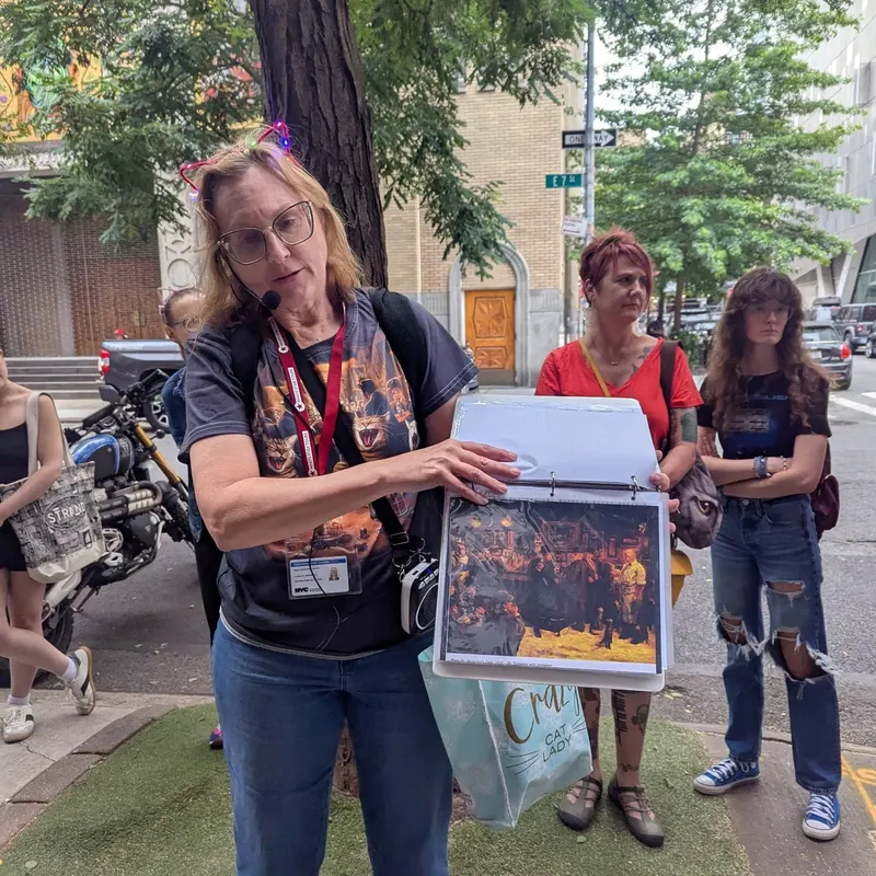 Walking tour group viewing historic cat scene on NYC street