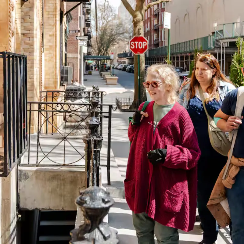 Cats About Town tour guests pause to look at a black cat in a window cage on Hicks Street, Brooklyn Heights