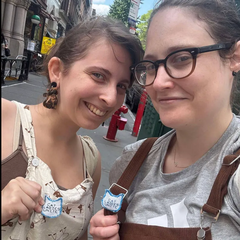 Two tour guests showing Cat Ladies Unite handmade pins