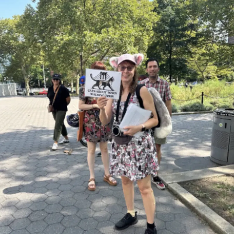 Tour guide Peggy with cat ears holding Cats About Town Walking Tours sign