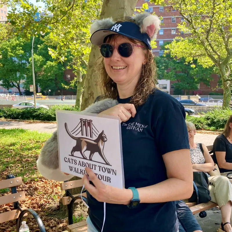 Tour guide Peggy in Yankees cap with cat ears holding tour sign